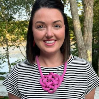 Young woman wearing a bright pink handwoven boating rope knot necklace with coastal backdrop